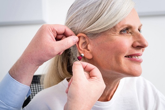 Ältere Frau bekommt ein Hörgerät eingesetzt, Hörakustiker Beratung und Hörhilfen.